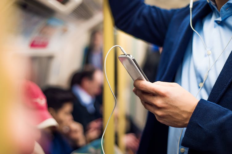 Man on train with phone and headphones