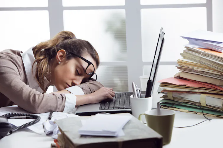 Tired woman sleeping on top of her laptop.
