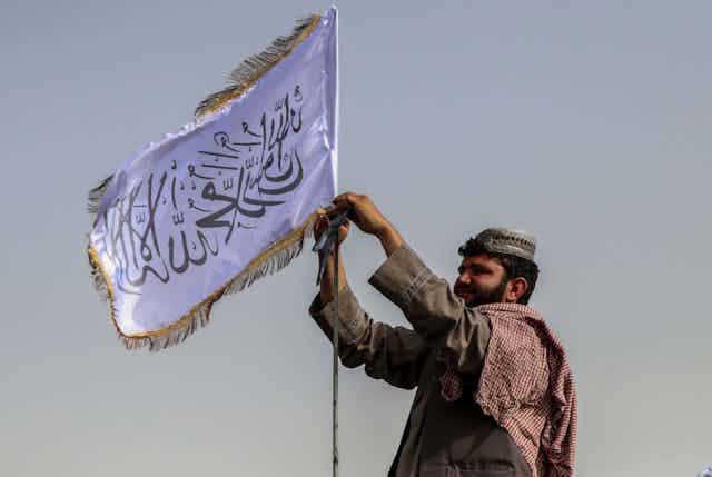 A man raising a Taliban flag in Kandahar, Afghanistan.