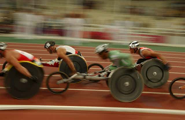 A blurred action shot of wheelchair racers on an Olympic track