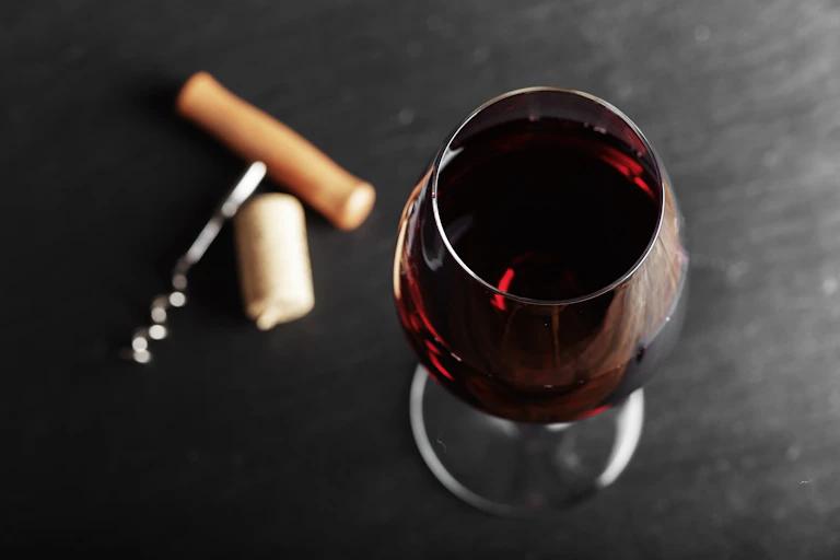A glass of red wine and a corkscrew