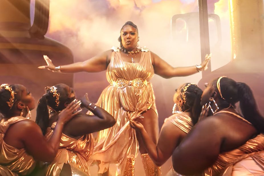 A group of women on their knees surround Lizzo.
