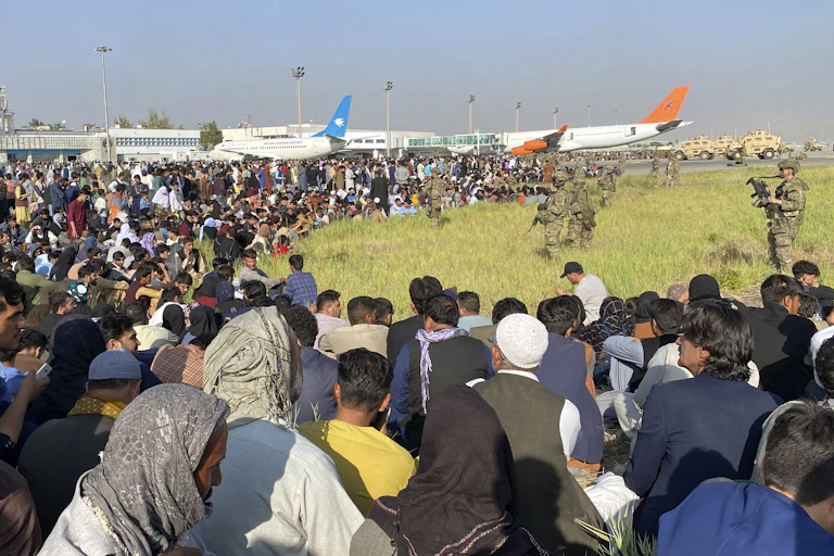 U.S. soldiers stand guard along the perimeter of the international airport in Kabul as hundreds of Afghans gather.