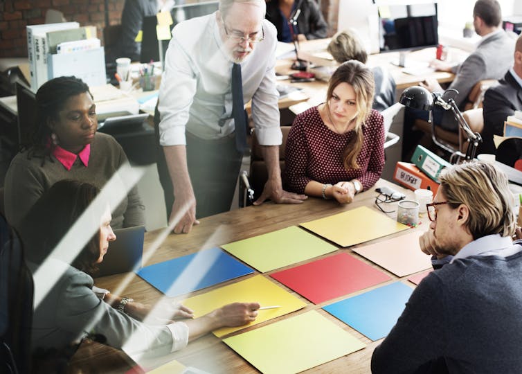 Teachers lead a discussion by students around a table