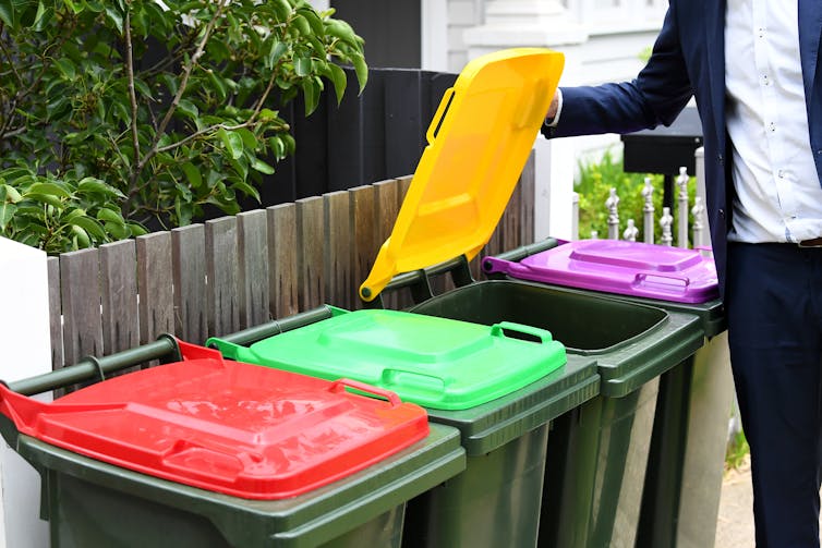 person opens lid of recycling bin