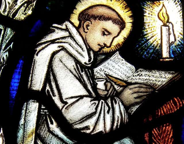 Stained glass window showing a monk writing at a desk.