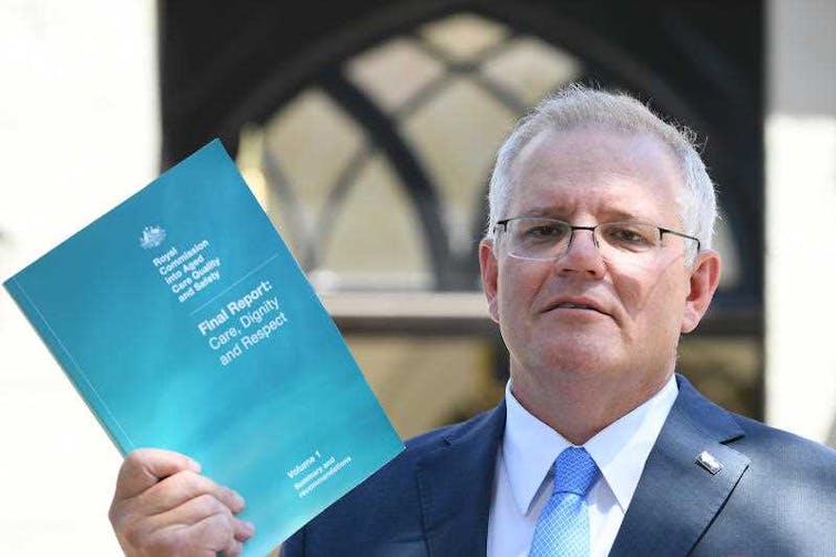 Prime Minister Scott Morrison holding the final report of the royal commission into aged care