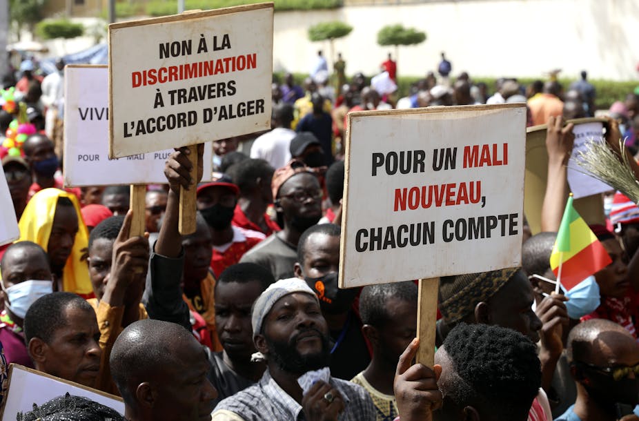 Men carry placards calling for a new Mali and an end to discrimination.