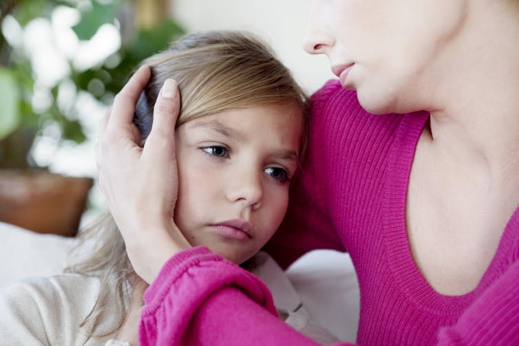 Una niña enferma abrazada por su madre