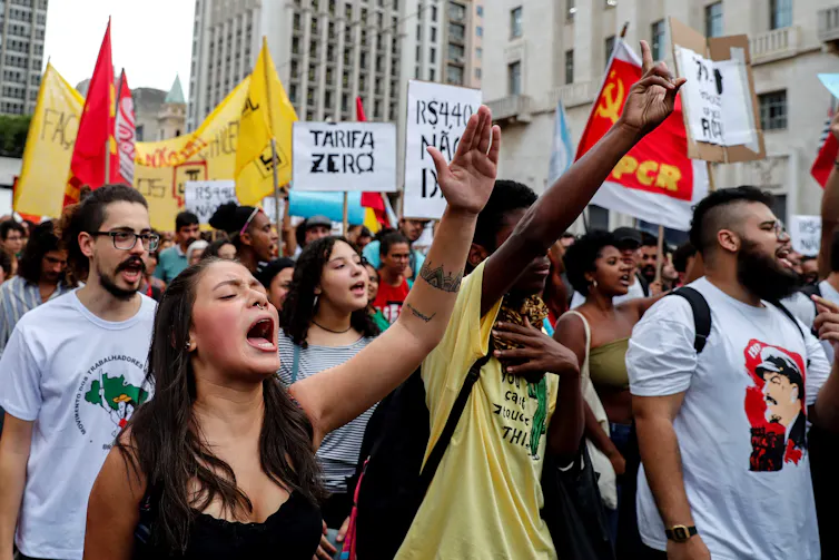 Brazilians, some in masks, some carrying banners, marching against a rise in bus fares, January 2020.