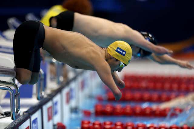 Two Paralympian swimmers dive into the swimming pool