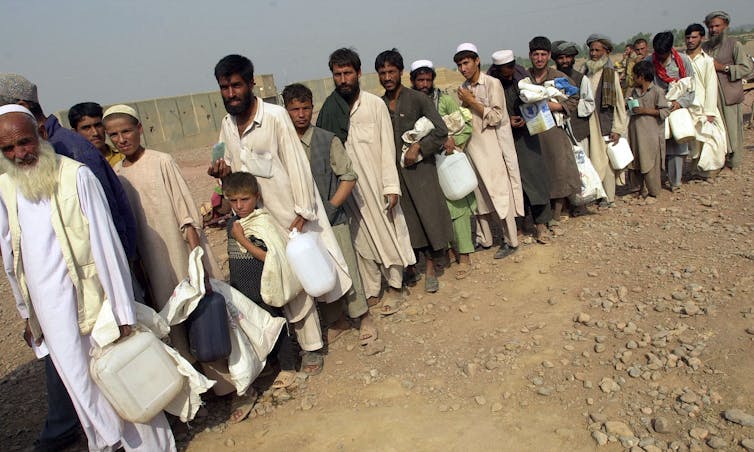 Afghans refugees line up for food disbursement at a camp in Pakistan in 2001.