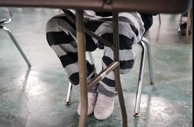Legs of a prisoner wearing black and white striped pants.