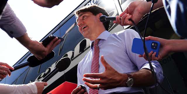 Justin Trudeau entouré de micros tendus