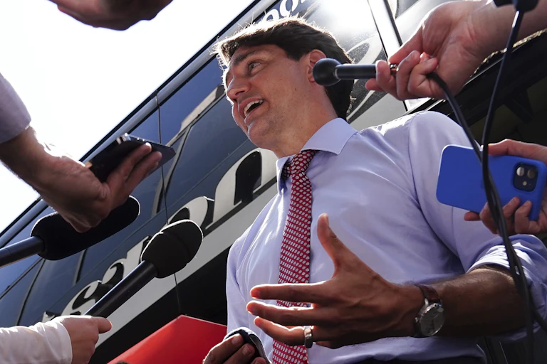 Justin Trudeau entouré de micros tendus