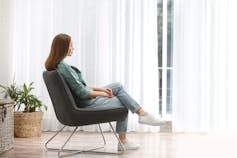 Woman in casual clothes sitting in a chair near a window