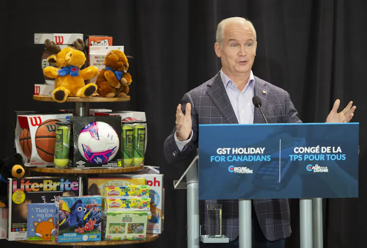 Erin O’Toole parle au micro, avec des jouets à ses côtés