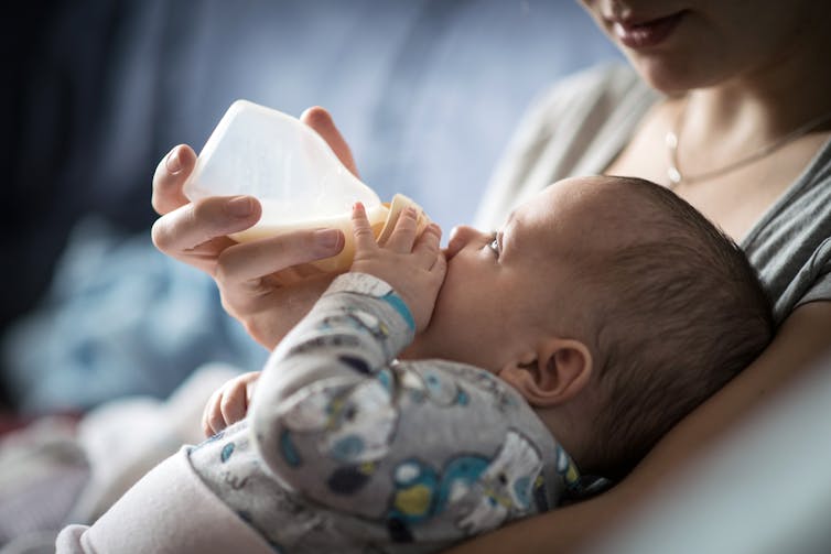 A woman feeds a baby with a milk bottle.