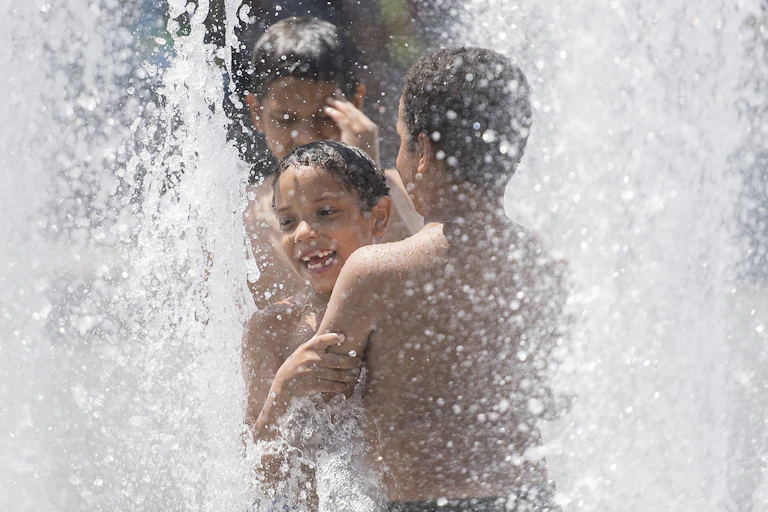 Des enfants jouent sous l'eau d'une fontaine