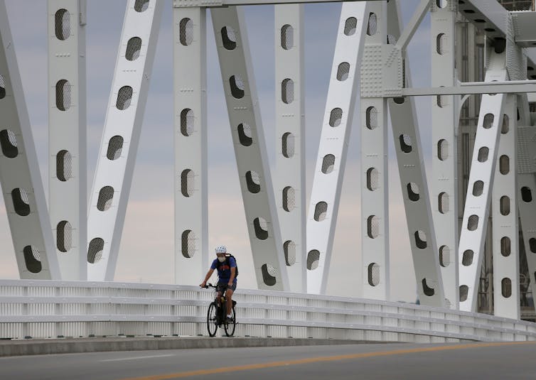 A cyclist rides over a bridge with metal girders.