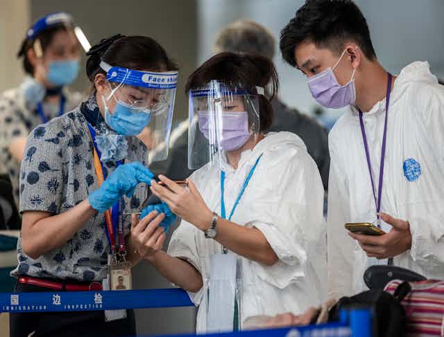 People wearing PPE look at a mobile phone