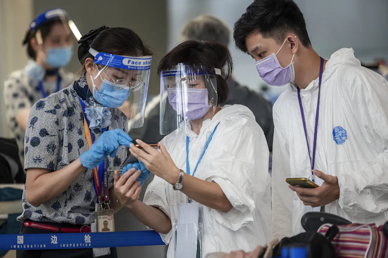 People wearing PPE look at a mobile phone