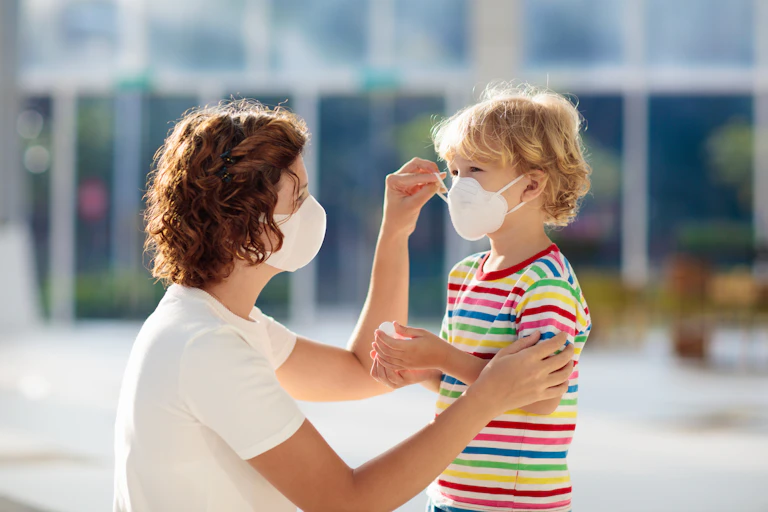 Mother putting a mask on her young son.
