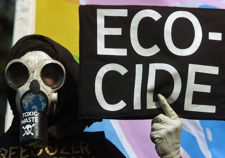 person in mask holds sign which says 'ecocode'