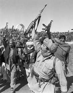 A group of fighters hold their guns aloft.