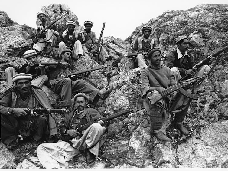 A group of mujahadeen fighters rest on a mountain.
