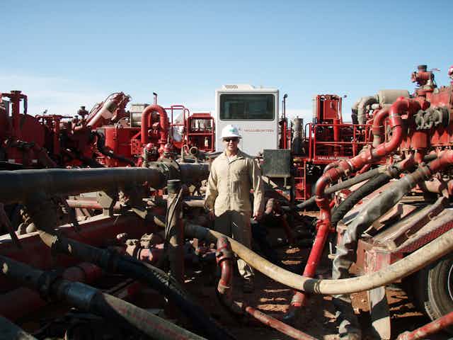 A worker surrounded by fracking equipment