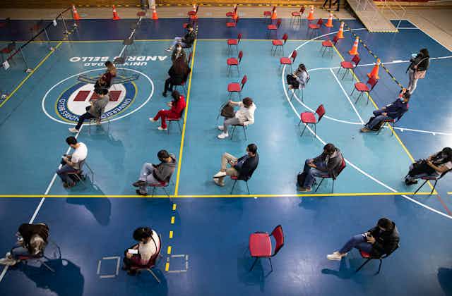 People sit in rows of chairs in a gym.