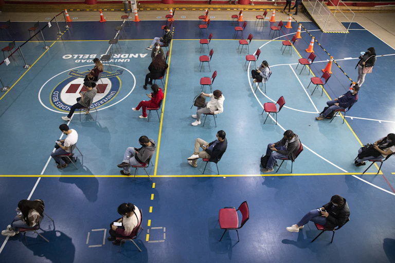 People sit in rows of chairs in a gym.