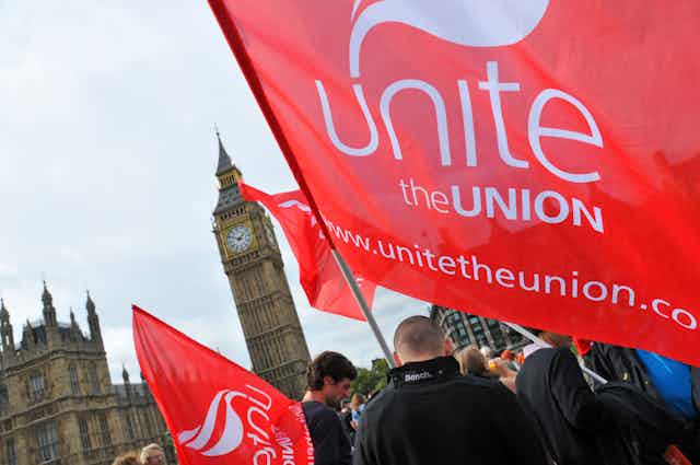 A man waves a Unite the union flag in front of Westminster