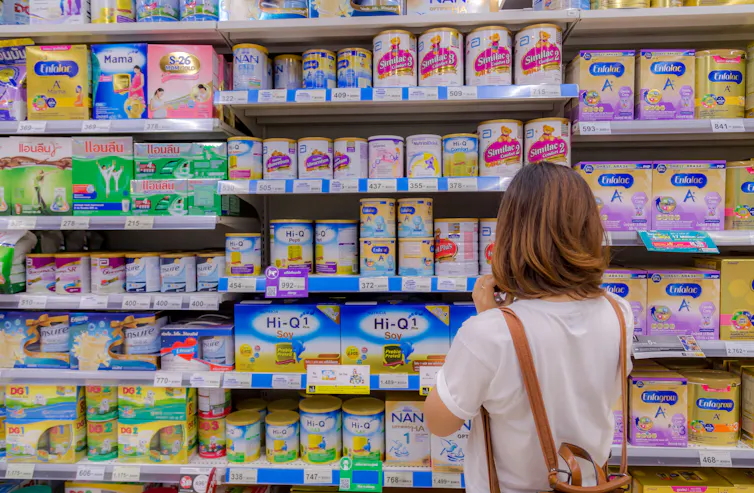 A woman browses infant formula at a grocery store.