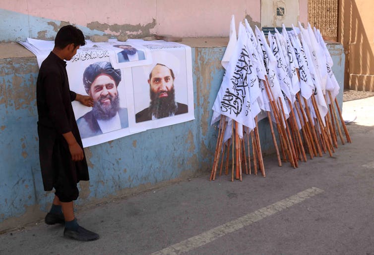 A man selling posters showing Taliban supreme commander Mullah Haibatullah Akhunzada and Taliban flags in Kabul.