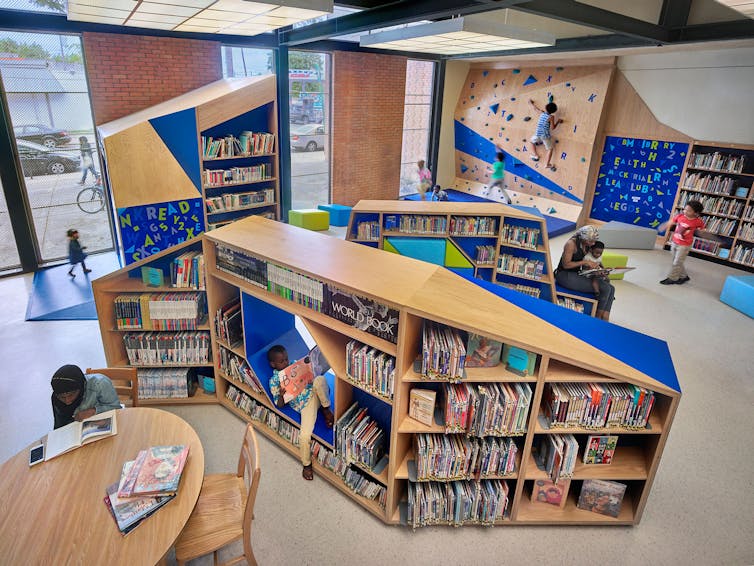 Children read books and play on climbing wall in library