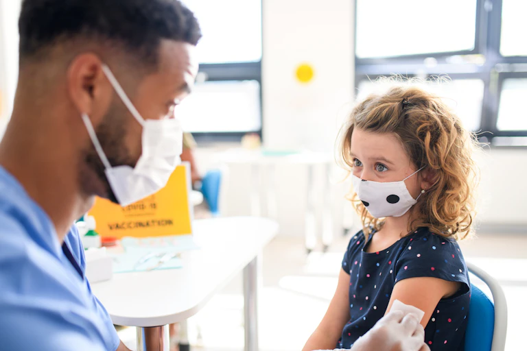 Child with face mask getting vaccinated against coronavirus