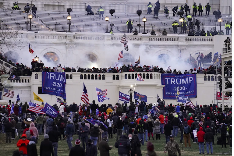 A crowd assembles outside the U.S. Capitol, waving U.S. flags and flags saying 'Trump'