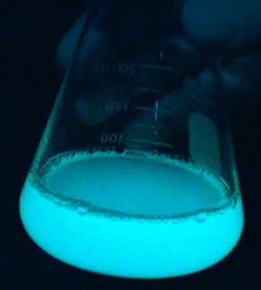A glass beaker glowing with a bluish light.