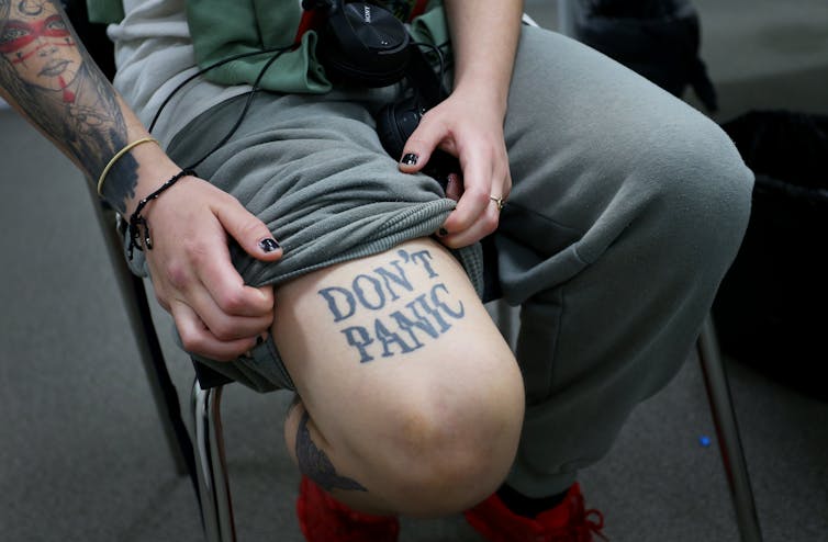 A woman shows off her pandemic tattoo that says, 'Don't Panic.'