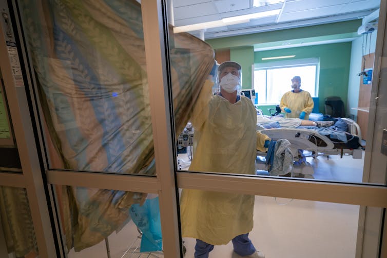 Nurses close the curtains of a patients room in the COVID-19 Intensive Care Unit at Surrey Memorial Hospital in Surrey, B.C.