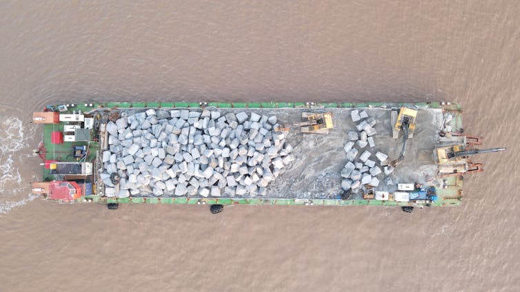 An aerial view of a barge carrying rocks