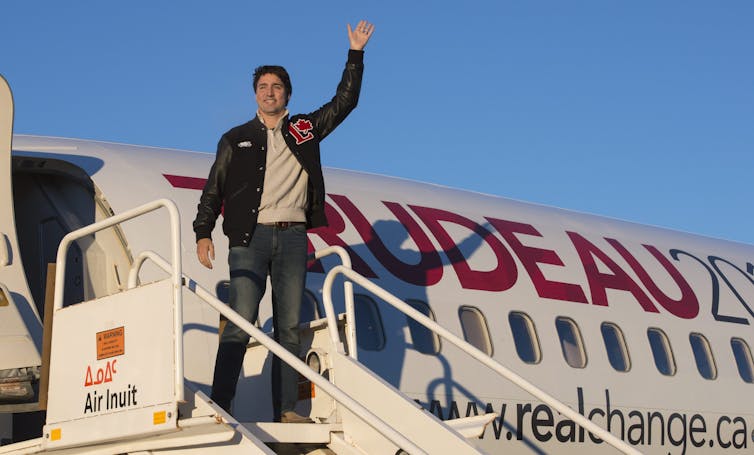 Trudeau waves as he steps off his campaign plane.