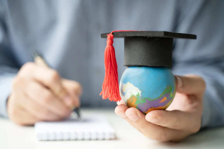 Estudiante sosteniendo una bola del mundo con birrete