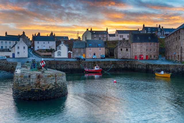 Port Soy harbour in Aberdeenshire at sunset under a bluey-grey and orange sky.