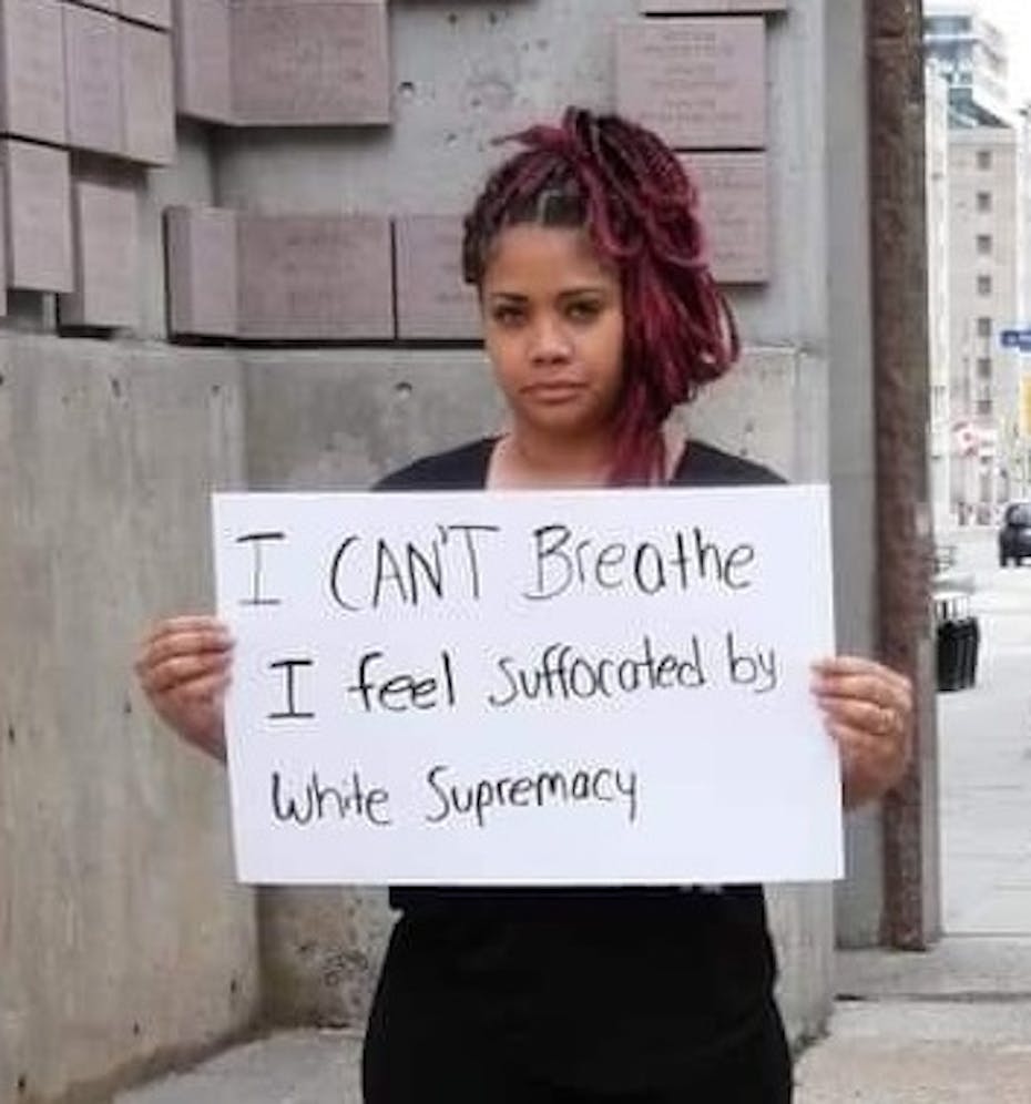 A woman holds a sign up that says 'I can't breathe.'