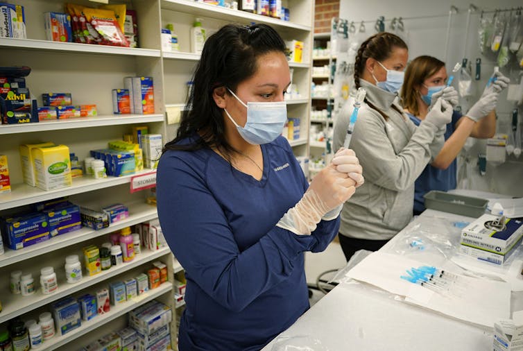 A medical worker holding a needle and vaccine vial.