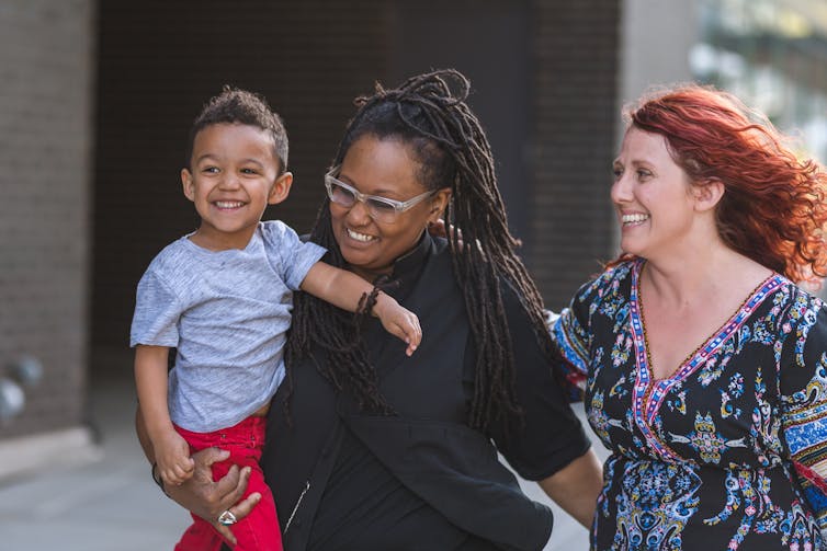 Two moms walk with young boy