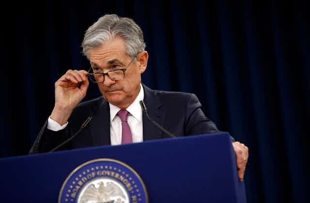 Federal Reserve Board Chair Jerome Powell fiddles with his glasses while giving a speech.